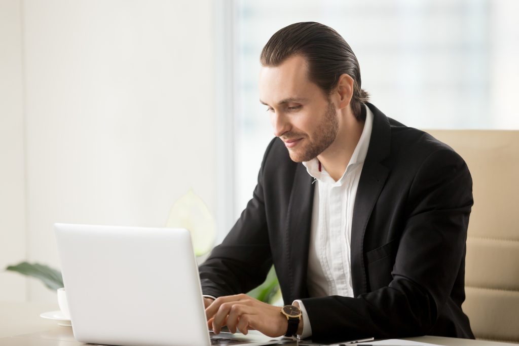 Empresario escribiendo en una computadora portátil en el escritorio de la oficina