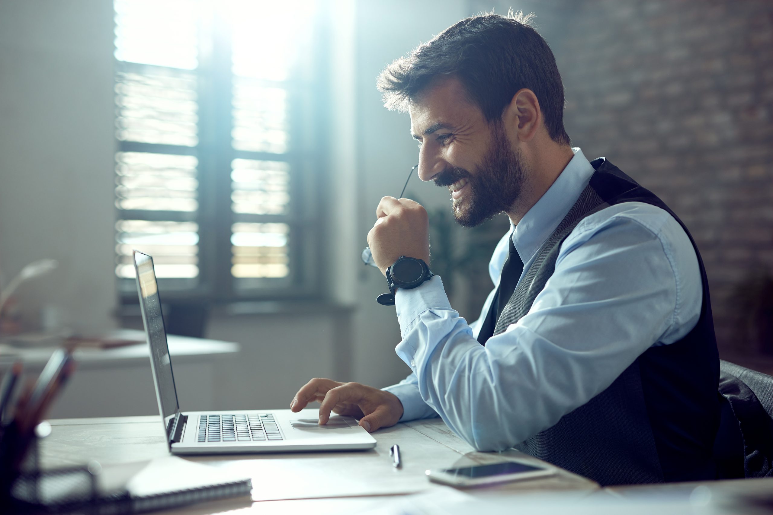 Joven hombre de negocios feliz trabajando en una computadora portátil en la oficina.